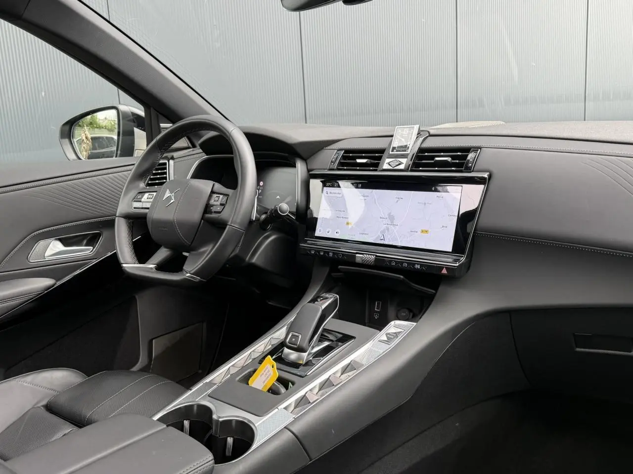 Intérieur DS7 2025 vu côté conducteur, tableau de bord noir avec écran tactile large et console centrale argentée.