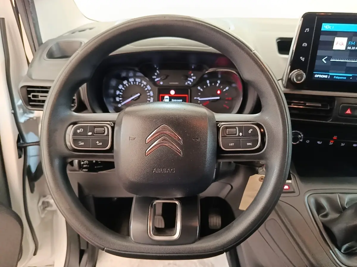 Vue intérieure centrée sur le volant multifonctions noir du Citroën Berlingo blanc avec tableau de bord et écran tactile.