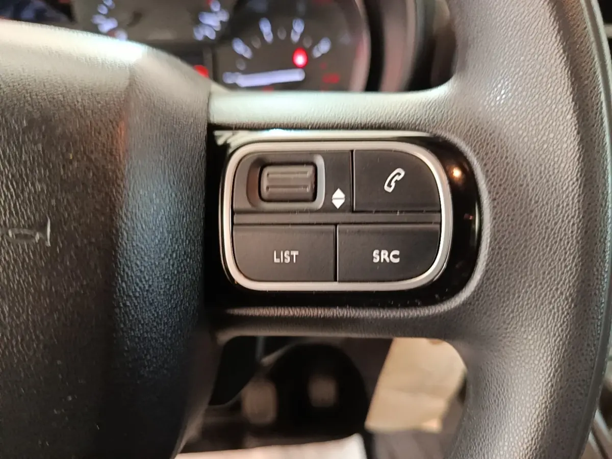 Gros plan sur les commandes multifonctions noires du volant réglable du Citroën Berlingo blanc, version 2021.