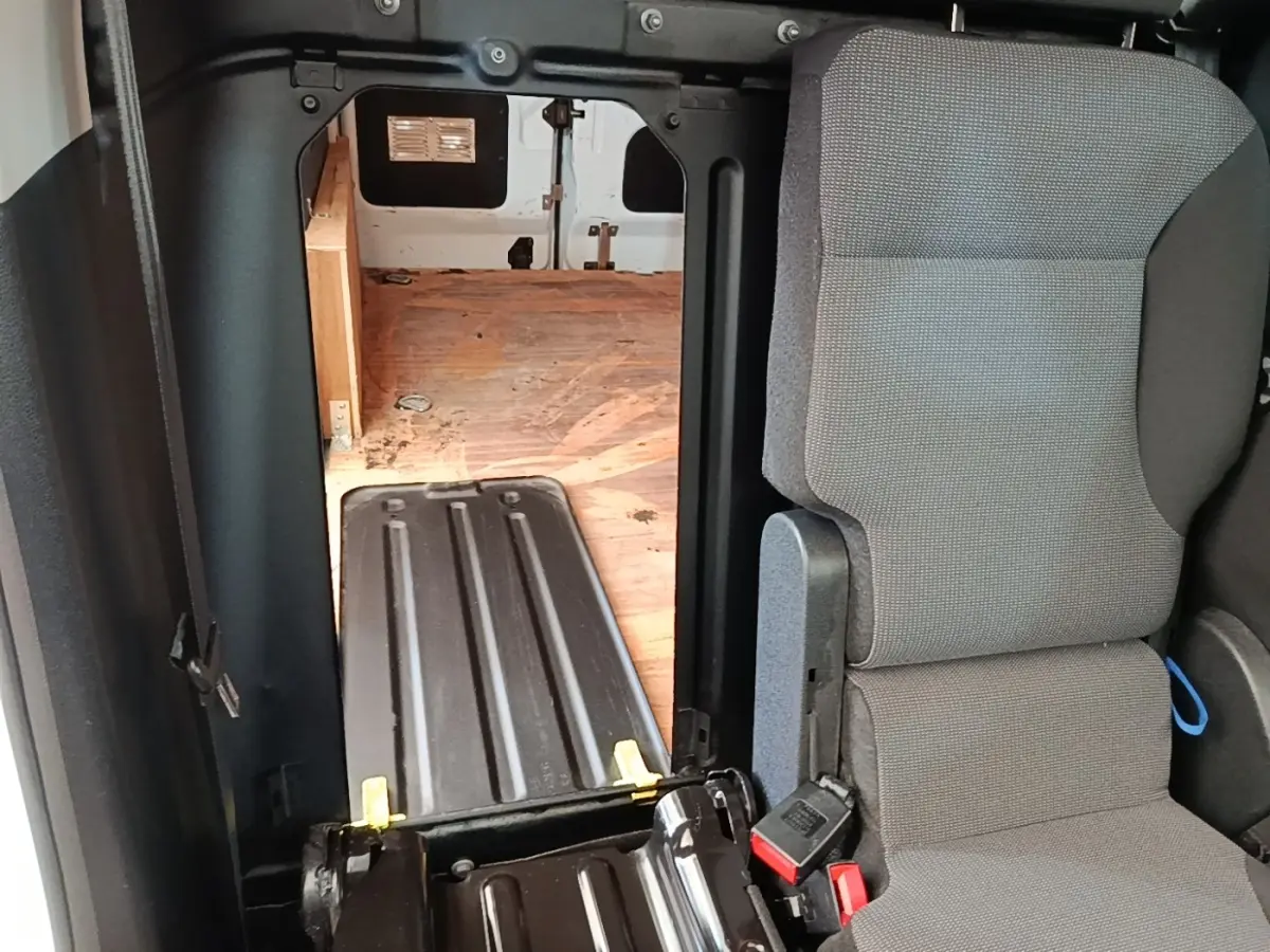 Vue intérieure du Citroën Berlingo blanc, montrant le siège passager et la cloison pleine vers l’espace de chargement en bois.