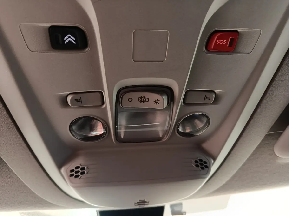 Plafonnier intérieur gris avec boutons d’éclairage, alarme SOS et commandes dans un Citroën Berlingo blanc, vue de dessous.