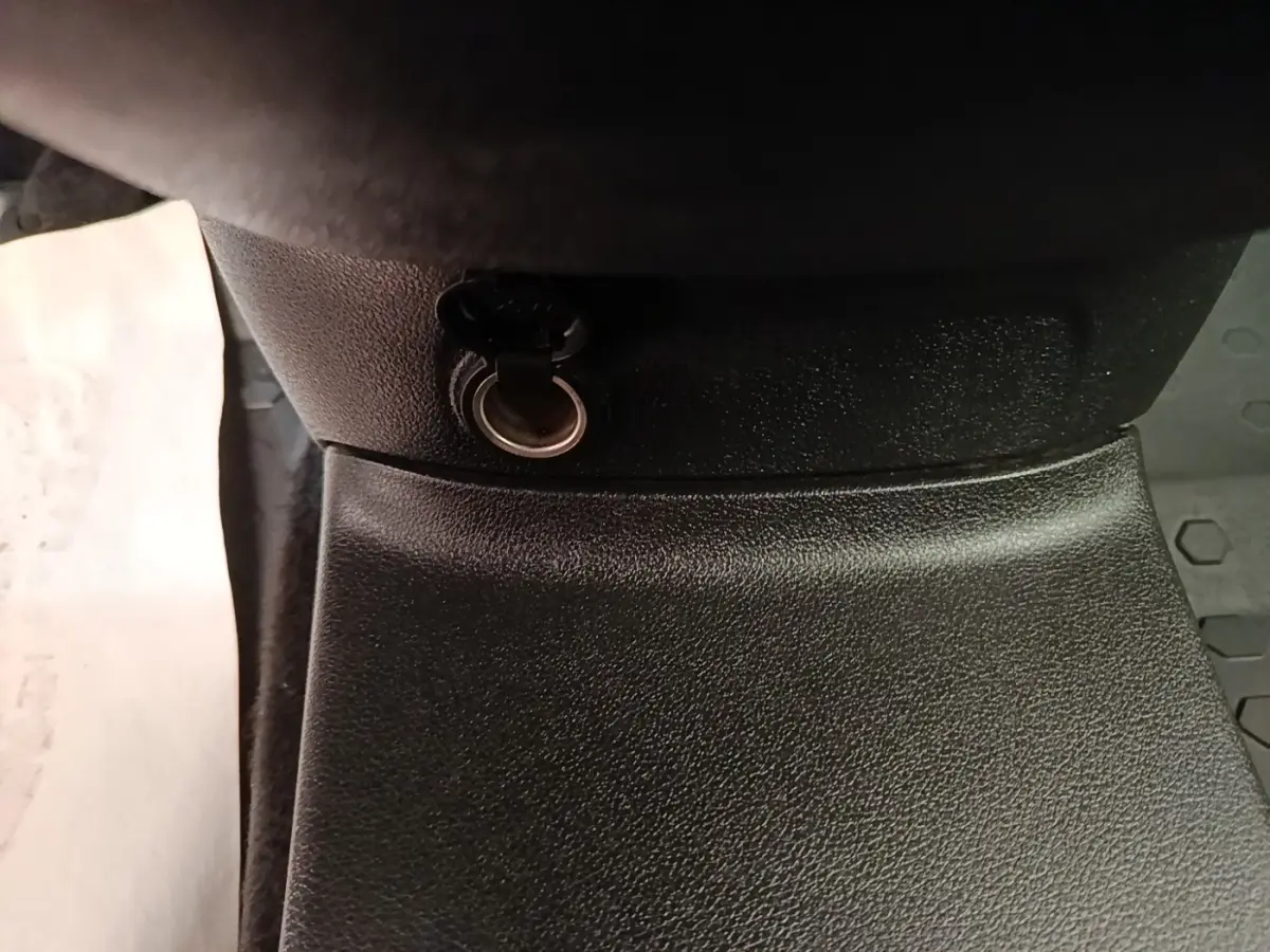 Prise 12V noire en gros plan dans l’habitacle du Citroën Berlingo blanc, vue centrée vers le bas.
