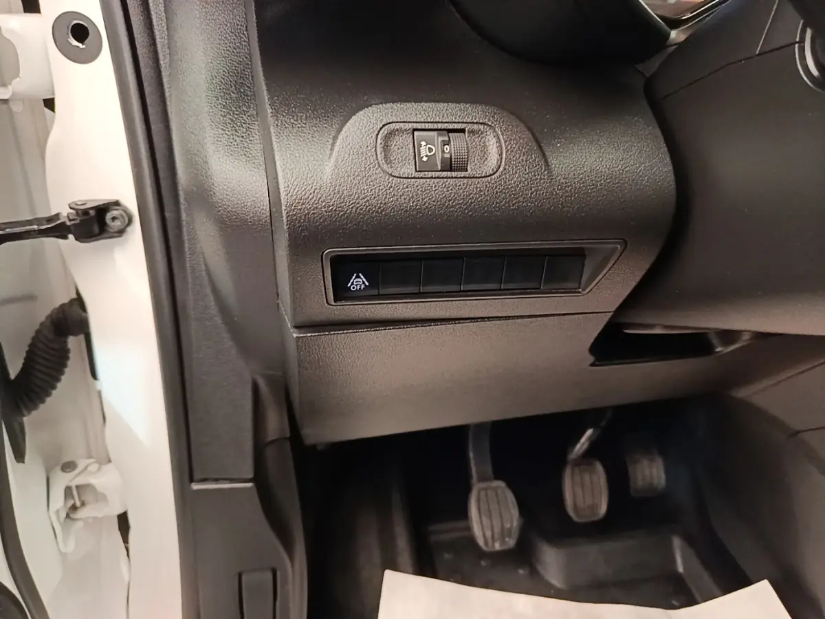 Détail intérieur côté conducteur du Citroën Berlingo blanc 2021 montrant les commandes d’éclairage et pédales manuelles.