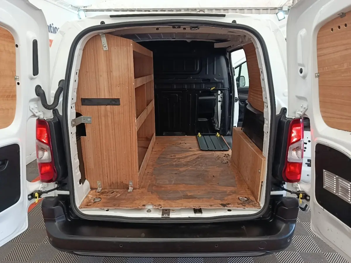 Vue arrière du Citroën Berlingo blanc 2021 avec portes ouvertes, aménagement bois intérieur et cloison pleine noire.