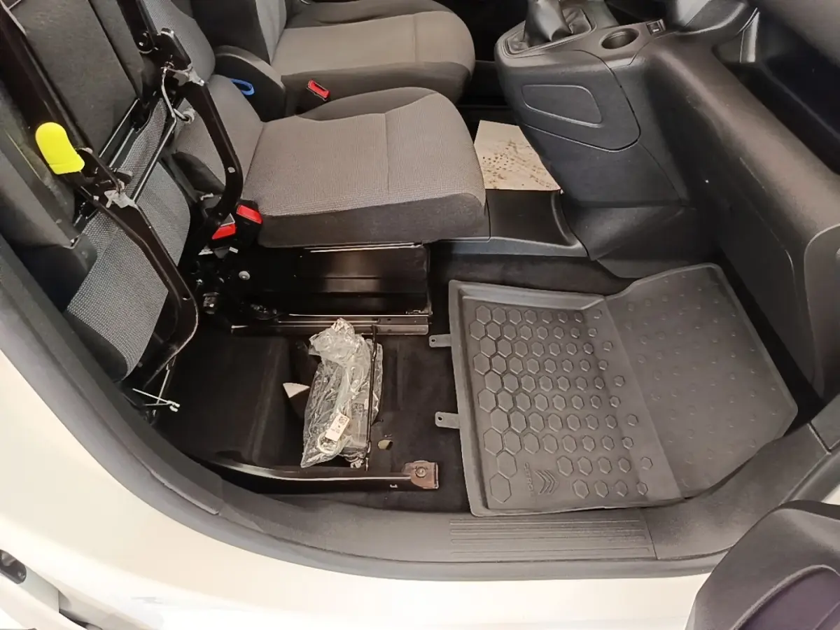 Vue intérieure côté passager avant du Citroën Berlingo blanc, siège relevé et tapis de sol caoutchouc visible.