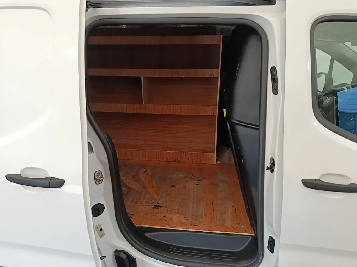 Vue latérale gauche d’un Citroën Berlingo blanc avec porte coulissante ouverte montrant l’aménagement intérieur en bois.