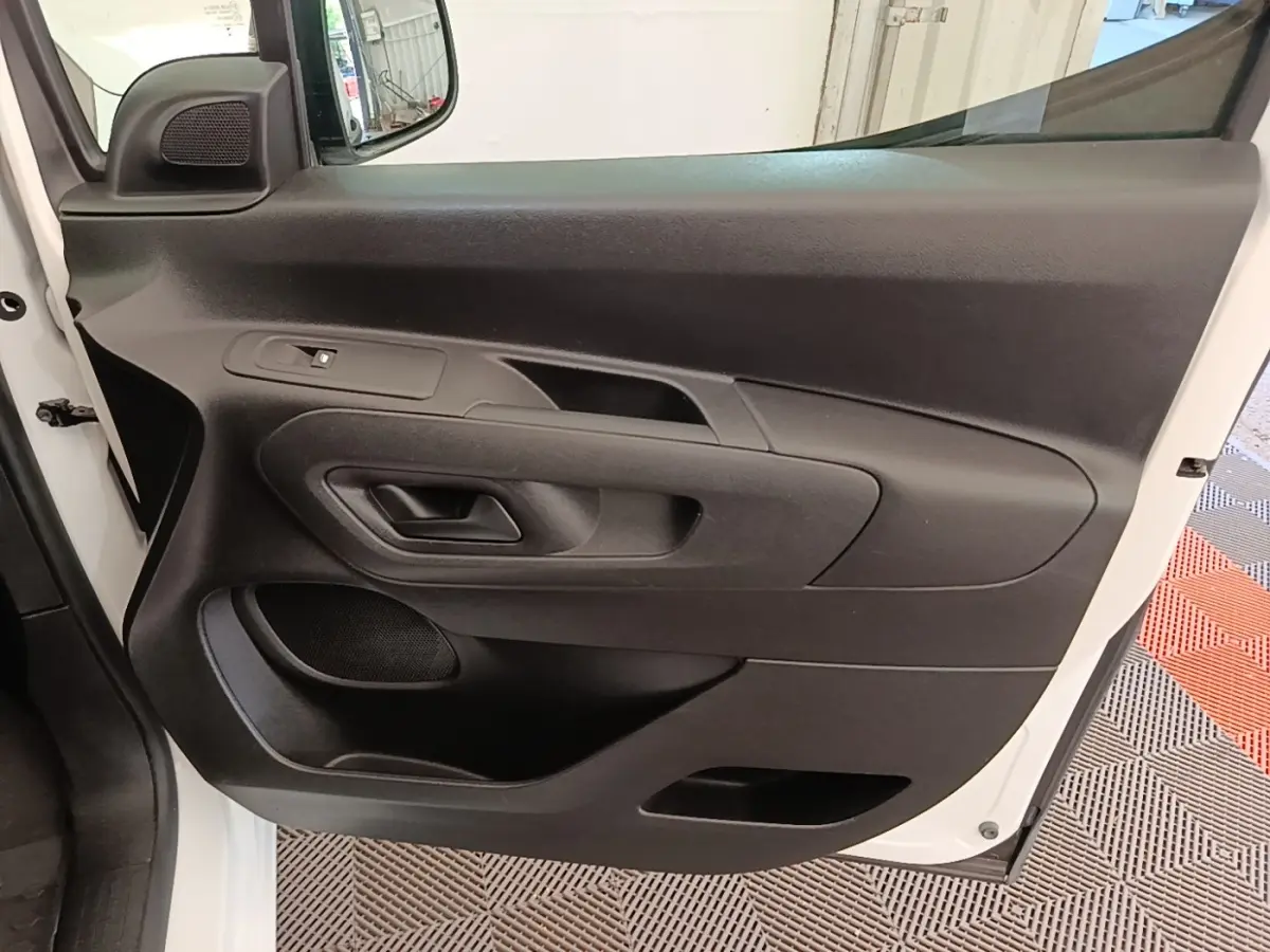 Vue rapprochée de la porte avant gauche noire du Citroën Berlingo blanc, avec poignée et commande de vitre.