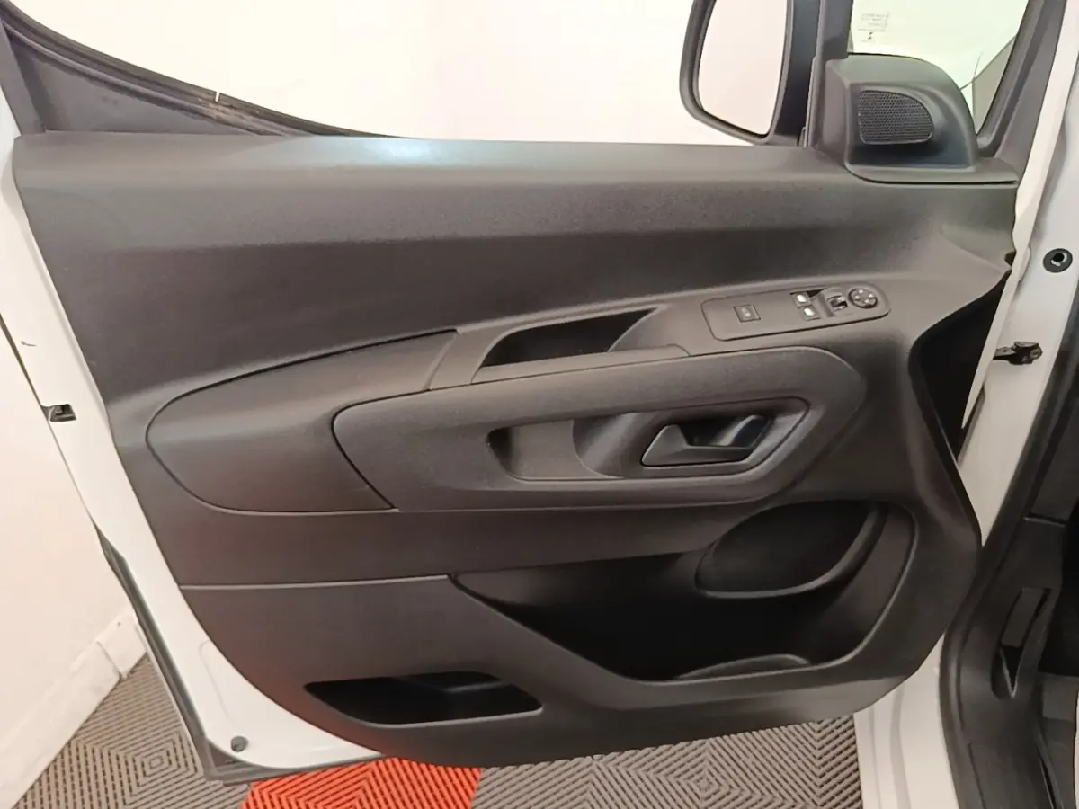 Porte avant gauche ouverte d’un Citroën Berlingo blanc, montrant les commandes électriques et la poignée intérieure noire.