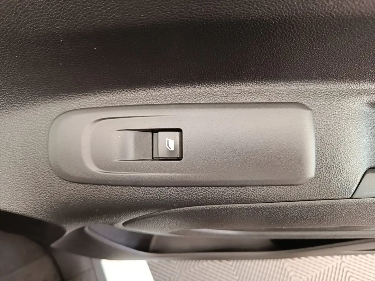 Gros plan sur le bouton de commande de la vitre électrique côté conducteur dans une Citroën Berlingo blanc, version 2021.