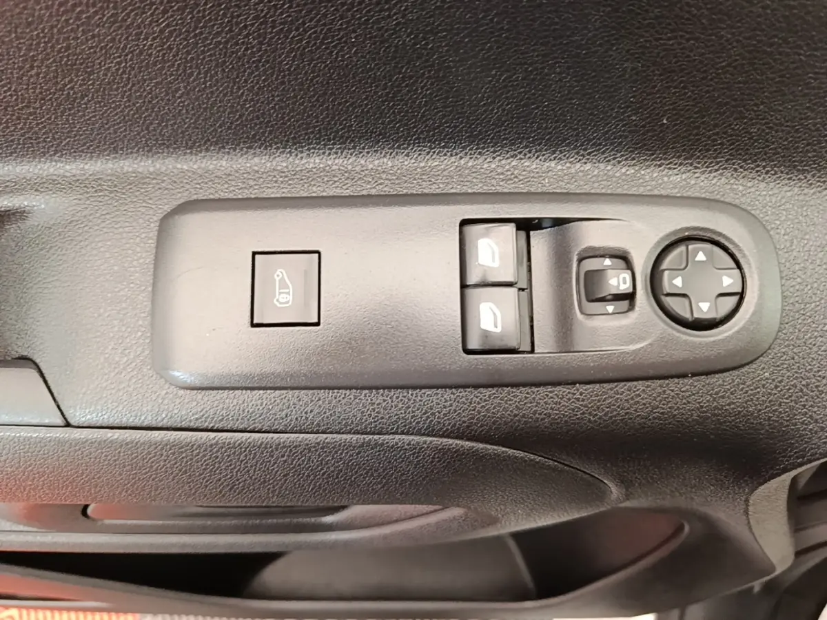Gros plan sur les commandes de réglage des rétroviseurs et vitres électriques côté conducteur du Citroën Berlingo blanc.