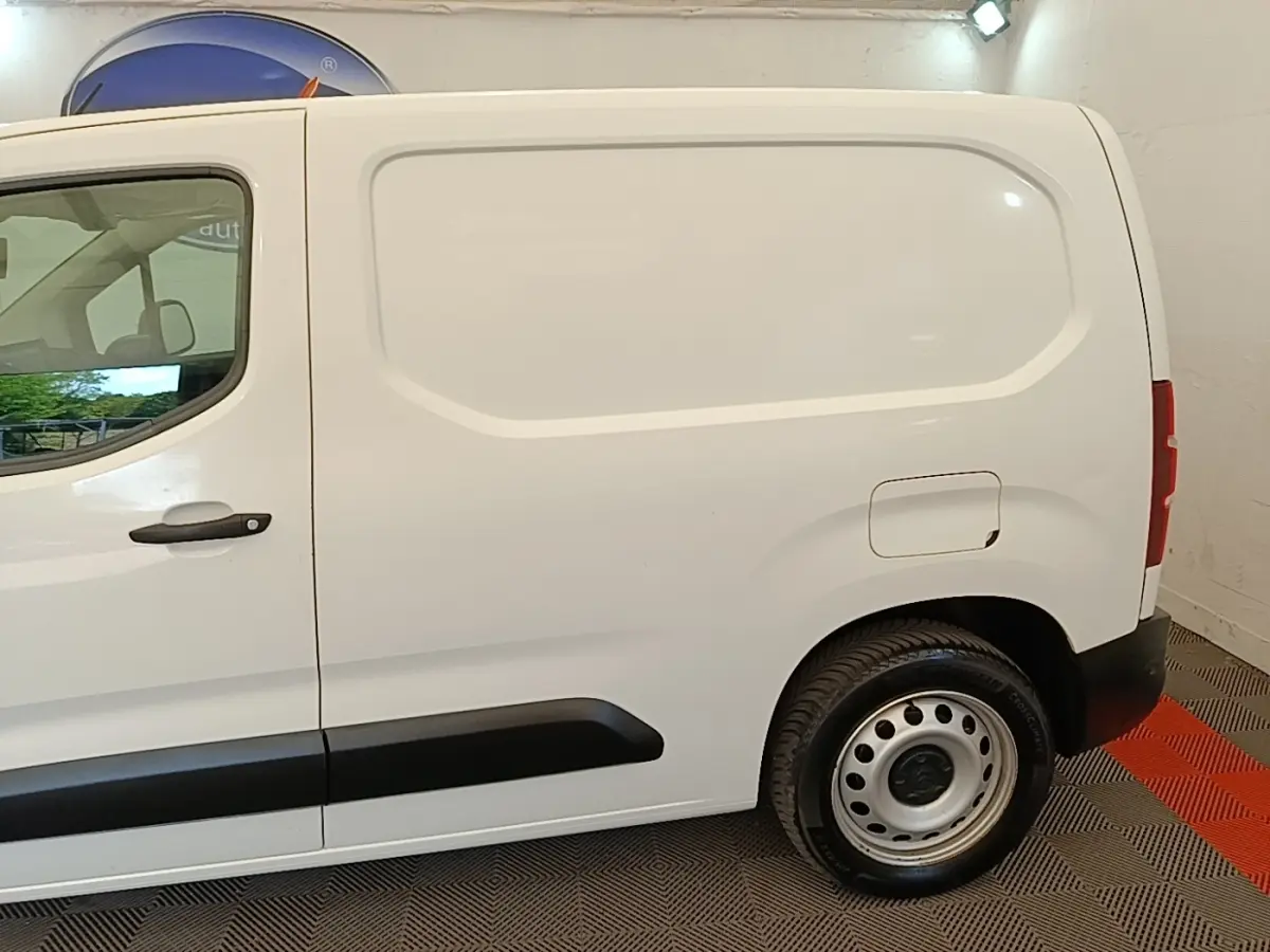 Vue de profil côté droit d’un utilitaire Citroën Berlingo blanc avec porte latérale pleine et jante acier.