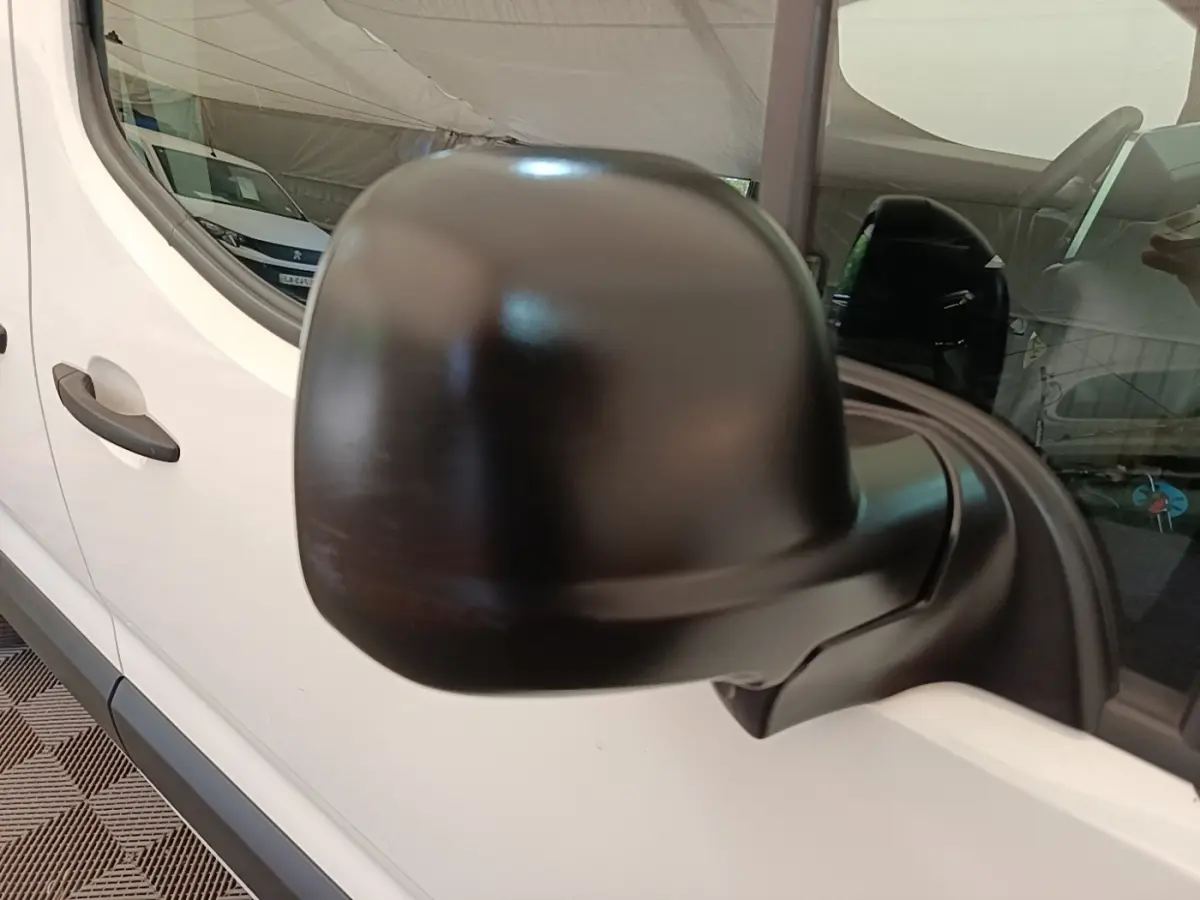 Rétroviseur noir en gros plan côté conducteur sur Citroën Berlingo blanc vue latérale partielle.