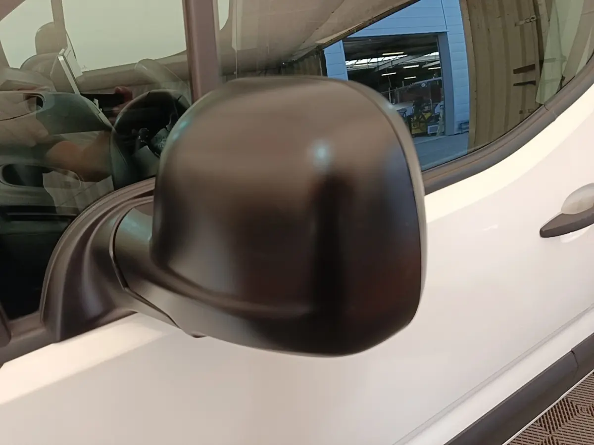 Gros plan sur le rétroviseur droit noir du Citroën Berlingo blanc, vue latérale avant du véhicule.
