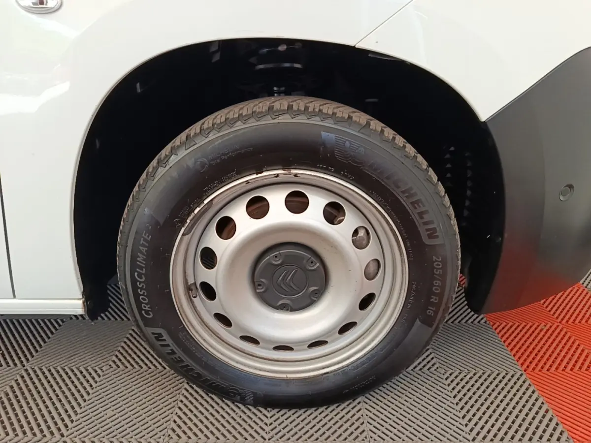 Gros plan sur la roue avant droite d’un Citroën Berlingo blanc avec jante acier et pneu Michelin.