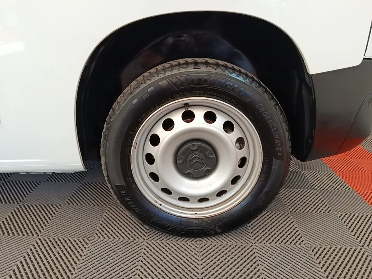 Gros plan sur la roue avant droite acier d’un Citroën Berlingo blanc, avec logo Citroën au centre de la jante.