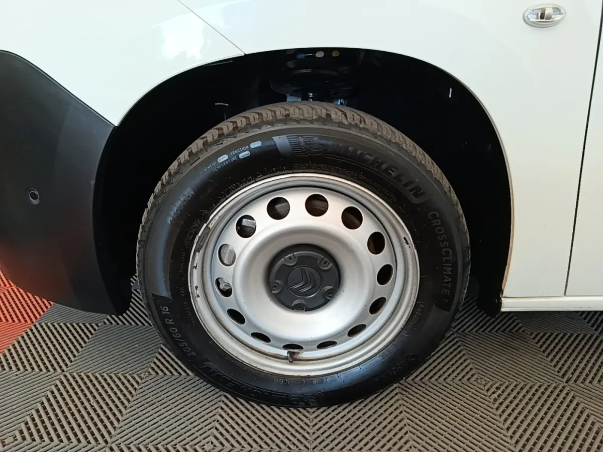 Gros plan sur la roue avant droite acier d’un Citroën Berlingo blanc, avec pneu Michelin CrossClimate visible.