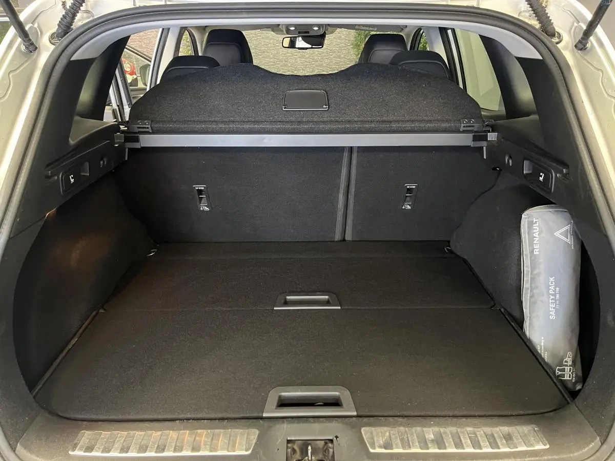 Coffre ouvert d'un Renault Kadjar gris, vue arrière montrant la tablette cache-bagages et un kit de sécurité Renault.
