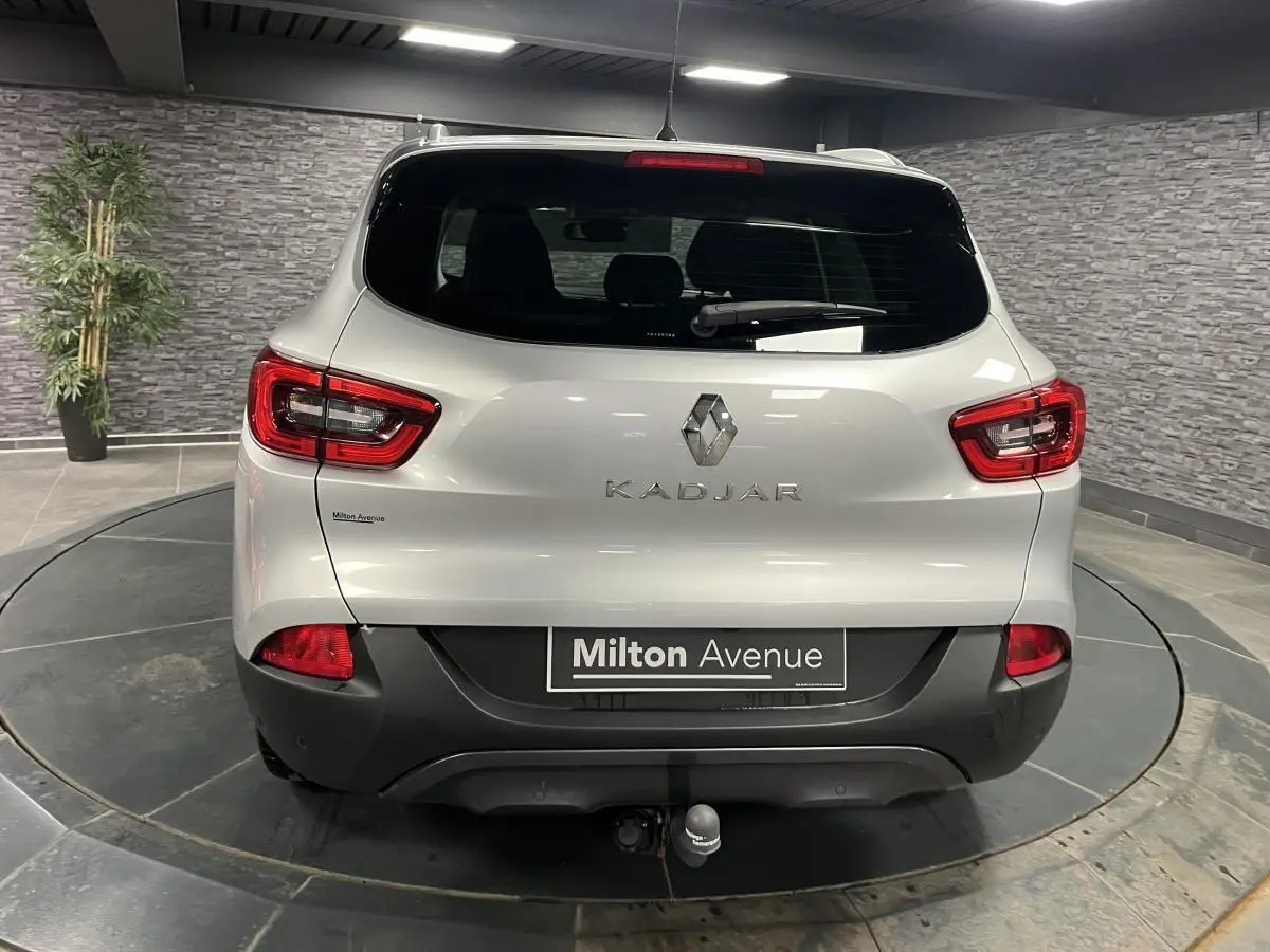 Vue arrière d'un Renault Kadjar gris avec attelage fixe et feux arrière LED dans un showroom.