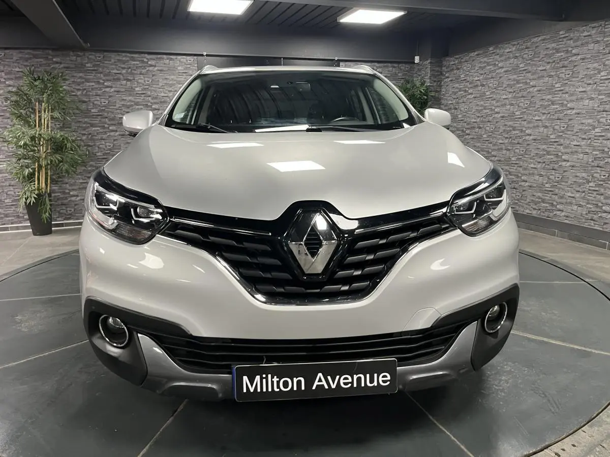 Vue de face d'un Renault Kadjar gris platine avec calandre noire et projecteurs Full LED dans un showroom.
