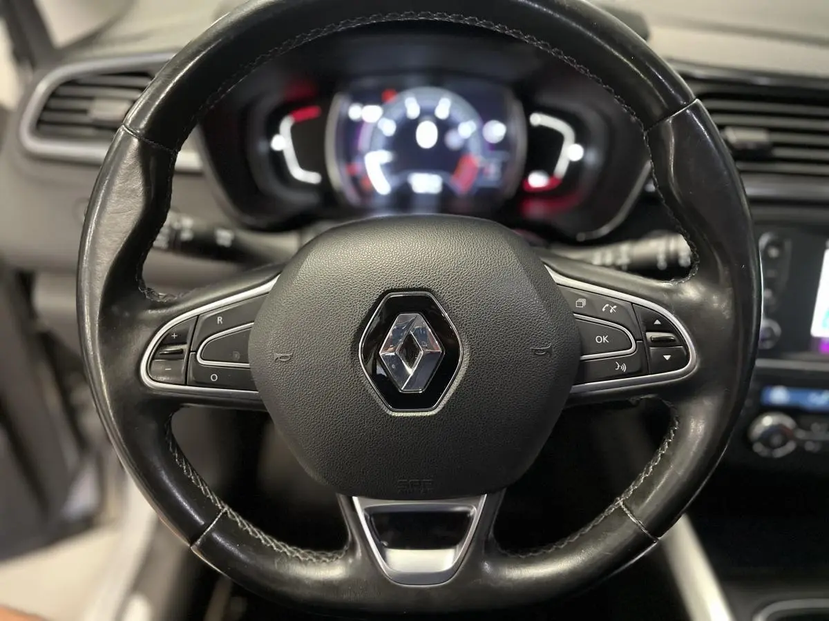 Volant cuir noir avec logo Renault au centre, tableau de bord numérique flou en arrière-plan du Renault Kadjar 2017.