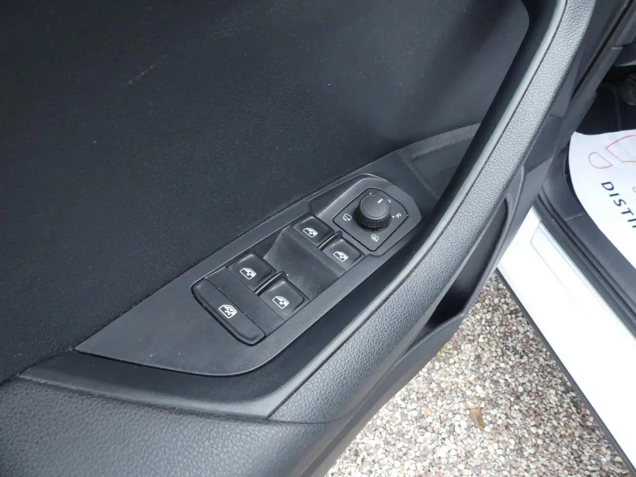 Gros plan sur les commandes de lève-vitres et réglage des rétroviseurs côté conducteur d'un Skoda Karoq blanc 2024.