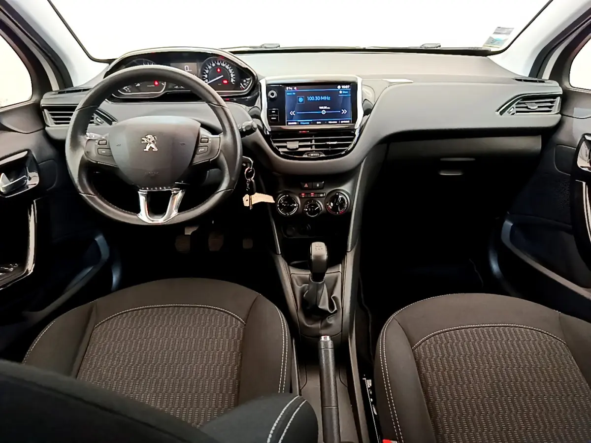 Vue intérieure avant du Peugeot 208 blanc 2019, volant cuir multifonctions et écran tactile central visible.