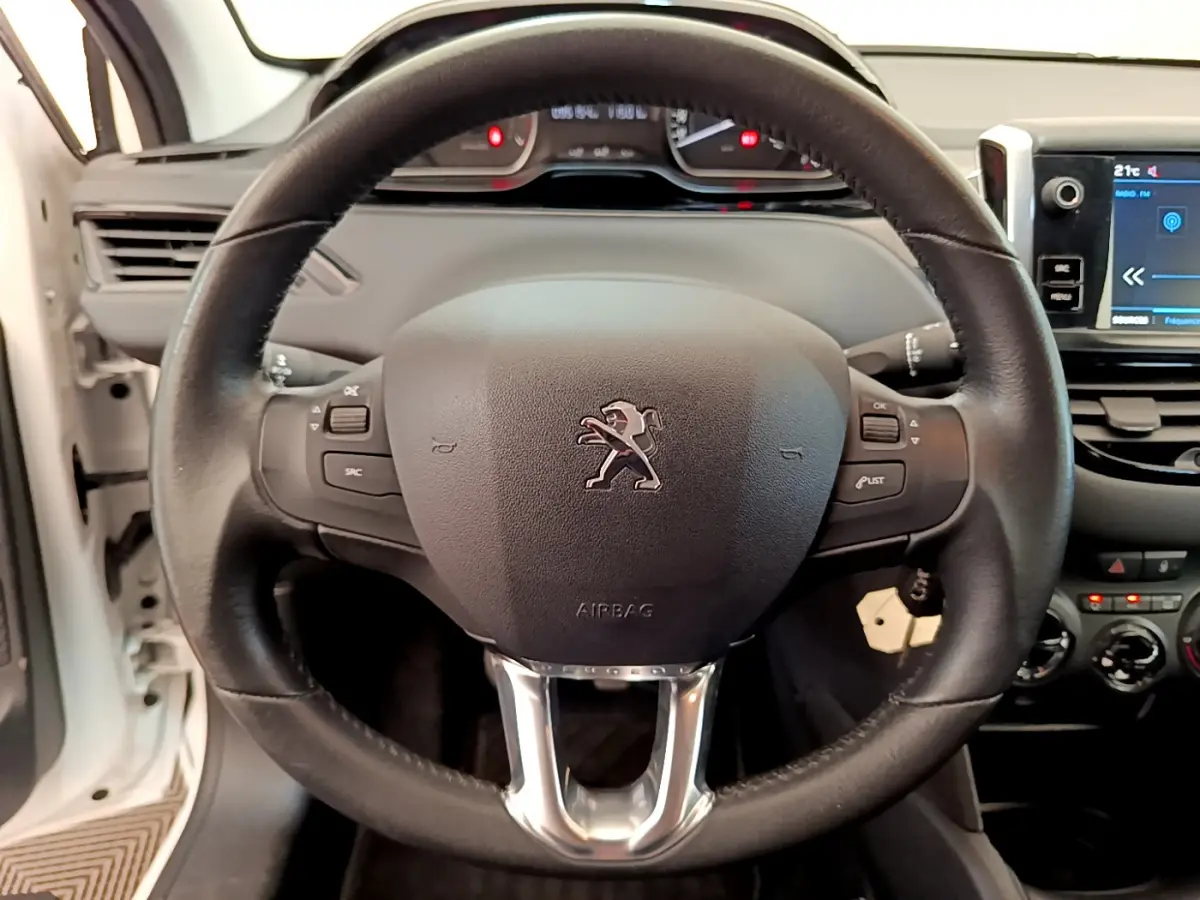 Vue rapprochée du volant cuir noir de la Peugeot 208 Puretech 82 Signature 2019 avec tableau de bord et écran tactile.