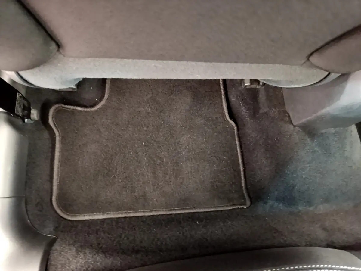 Vue rapprochée du tapis de sol noir sous le siège avant droit d'une Peugeot 208 Puretech 82 Signature blanche de 2019.