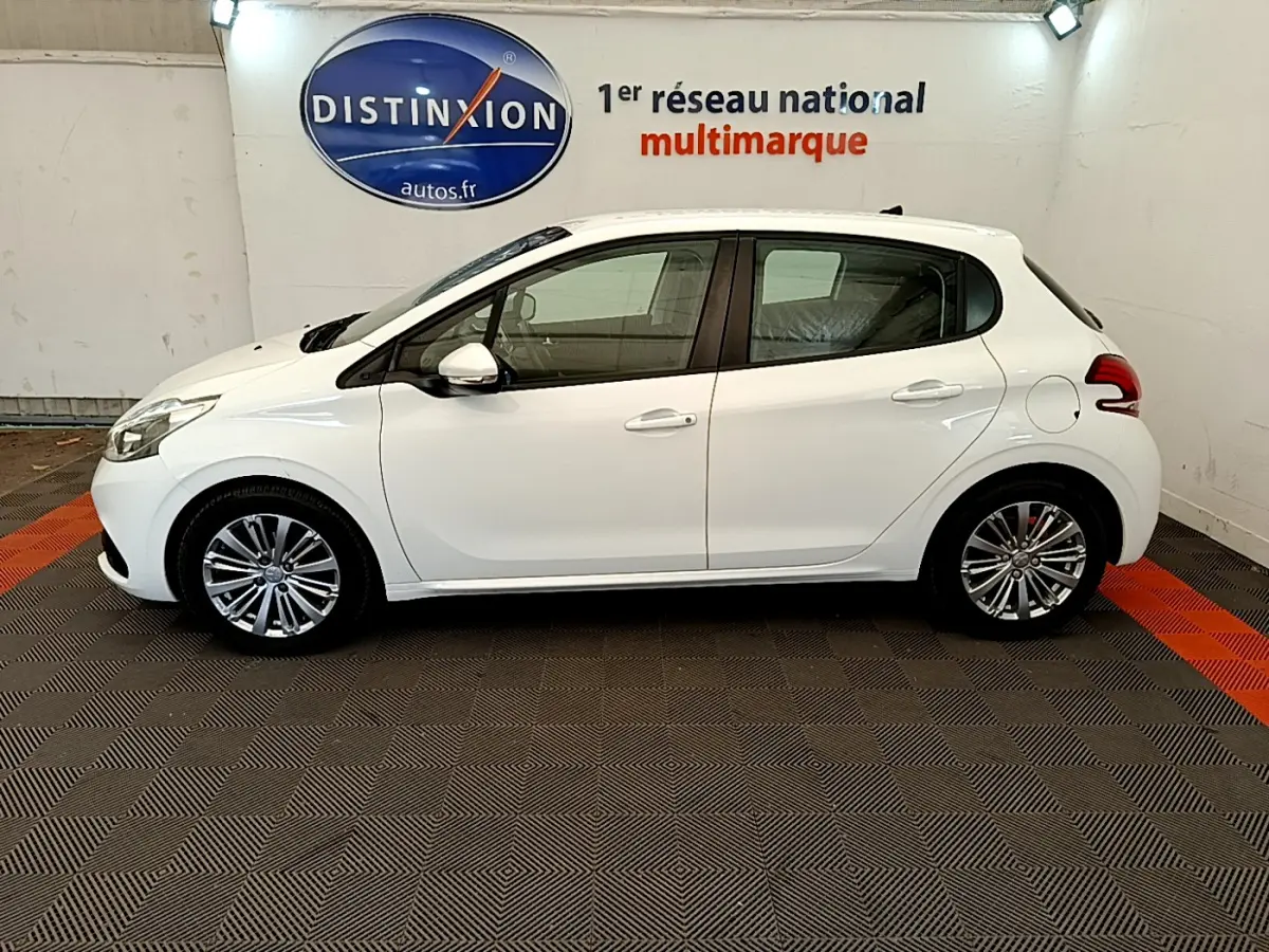 Profil latéral droit d'une Peugeot 208 blanche Puretech 82 Signature de 2019 dans un showroom multimarque.