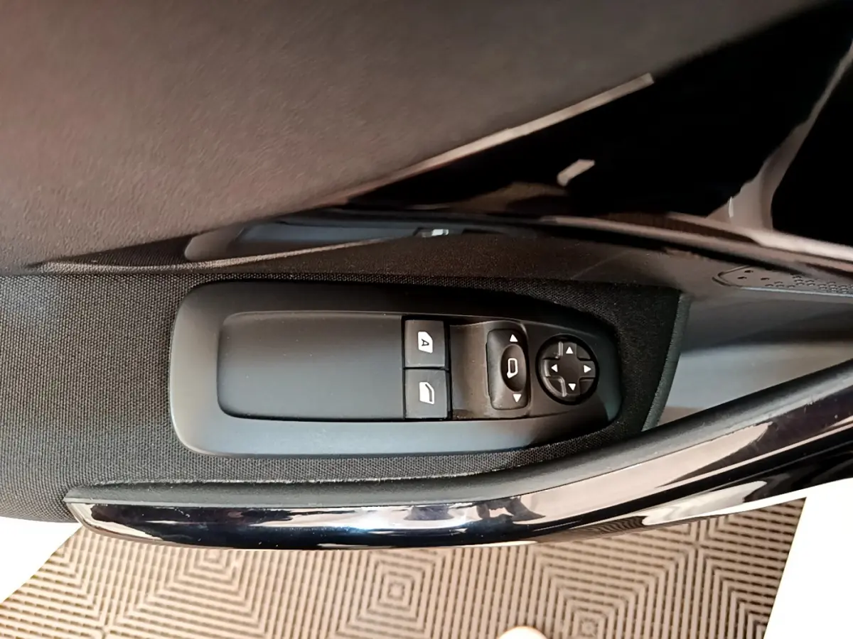 Commande des vitres électriques et réglage des rétroviseurs sur la porte côté conducteur d'une Peugeot 208 blanche