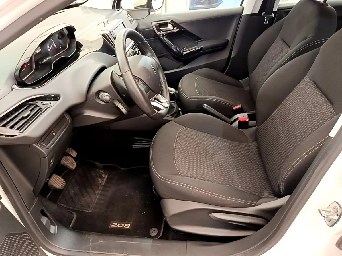 Intérieur avant droit de la Peugeot 208 Puretech 82 Signature 2019 avec sièges noirs et tableau de bord moderne.