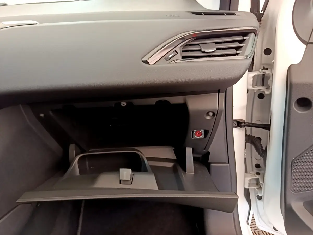 Intérieur côté passager de la Peugeot 208 blanche 2019, boîte à gants ouverte sous tableau de bord noir.