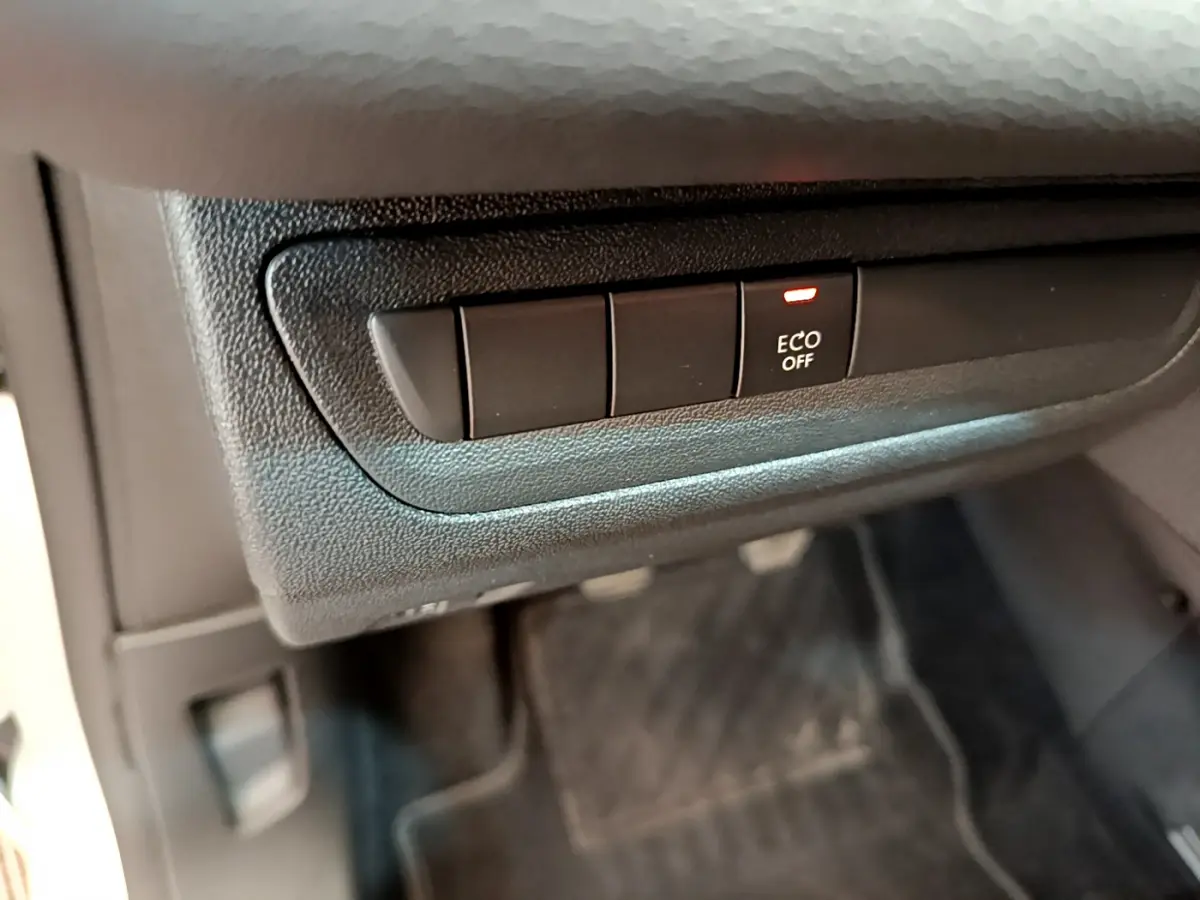 Gros plan sur le bouton ECO OFF dans l'habitacle noir d'une Peugeot 208 Puretech 82 Signature blanche de 2019.