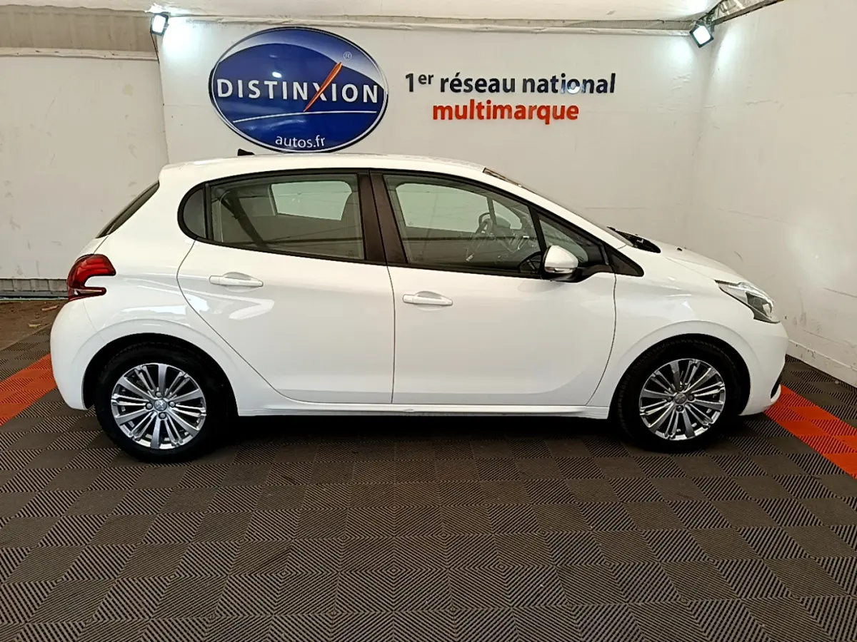 Profil latéral droit d'une Peugeot 208 Puretech 82 Signature blanche, avec jantes alliage et rétroviseurs chromés électriques.