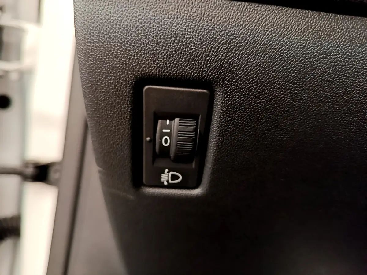 Gros plan sur le réglage manuel des phares dans une Peugeot 208 Puretech 82 Signature blanche de 2019.