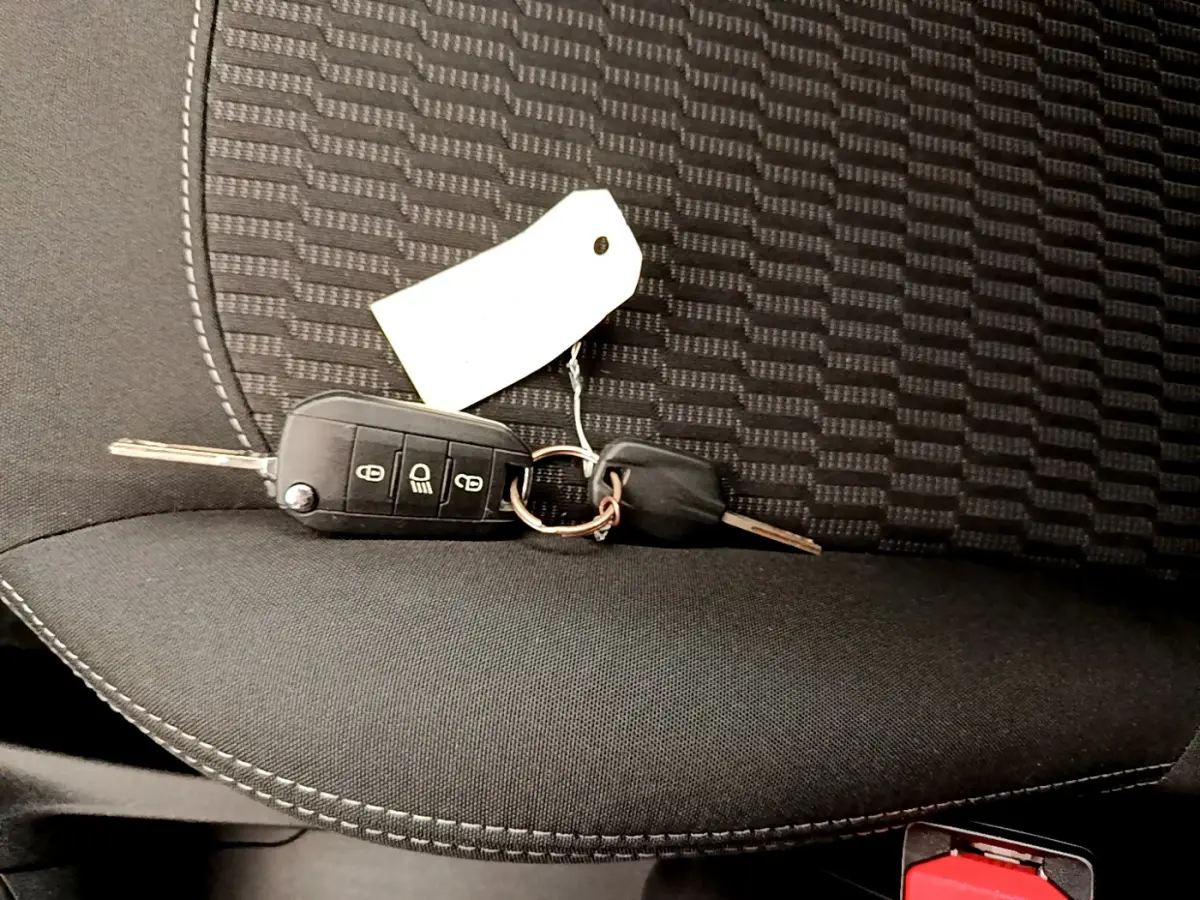 Clé de contact posée sur le siège avant en tissu noir de la Peugeot 208 Puretech 82 Signature blanche de 2019.