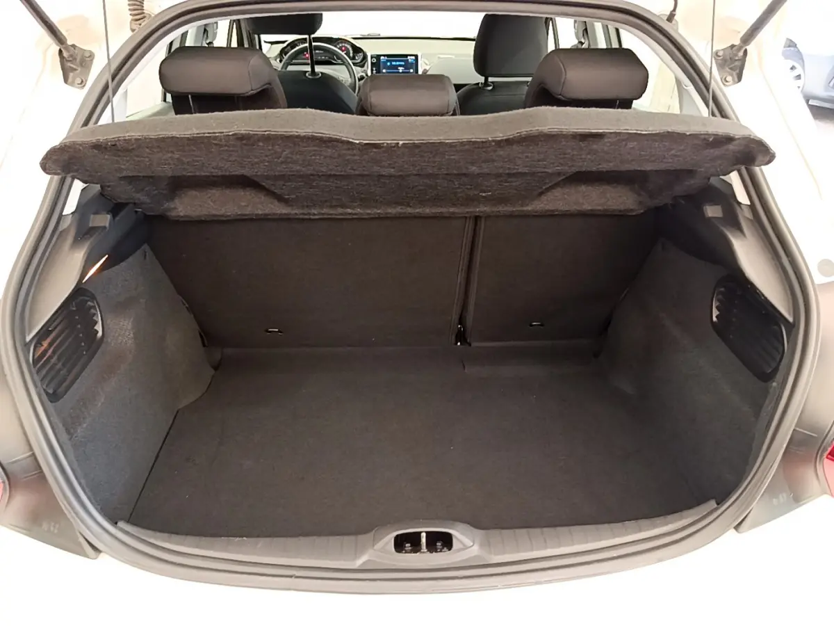 Coffre ouvert d'une Peugeot 208 blanche vue de l'arrière, montrant l'espace de chargement et les sièges arrière.