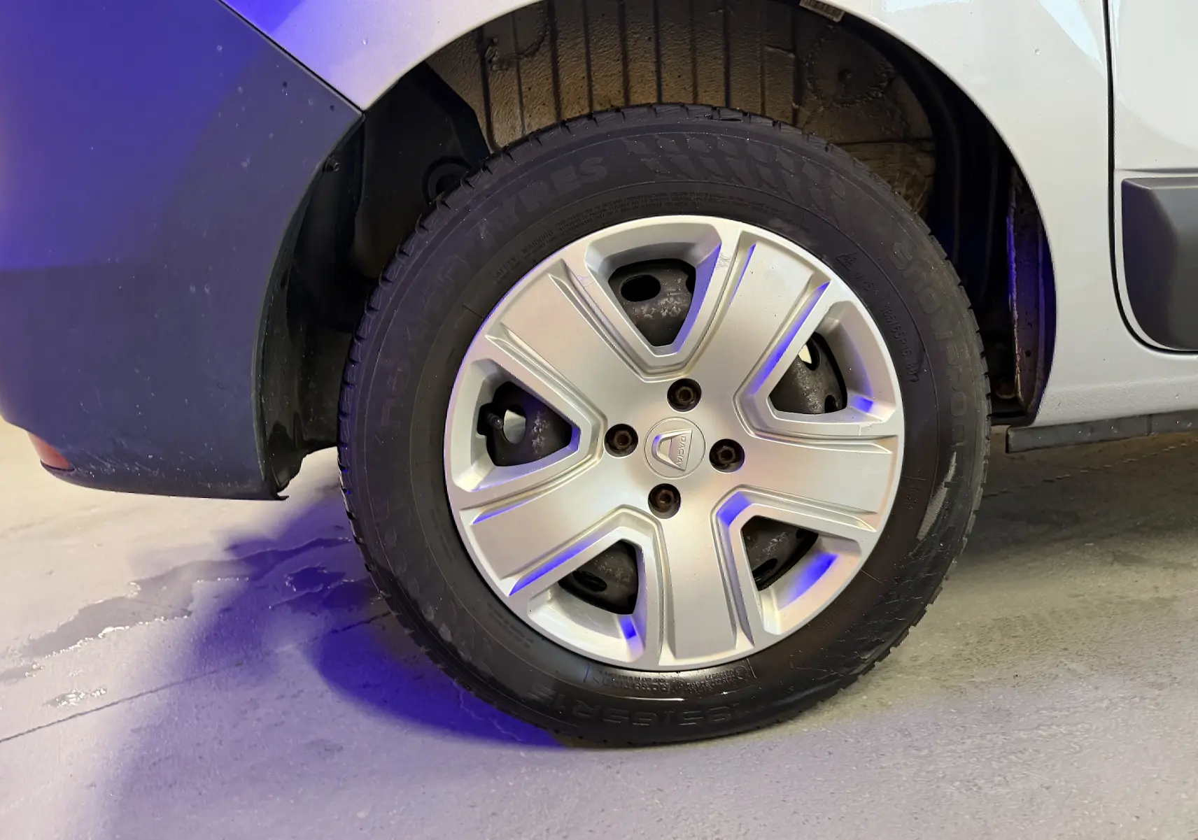 Gros plan sur la roue arrière gauche grise d'un Dacia Dokker 2019 avec enjoliveur argenté et logo Dacia au centre.