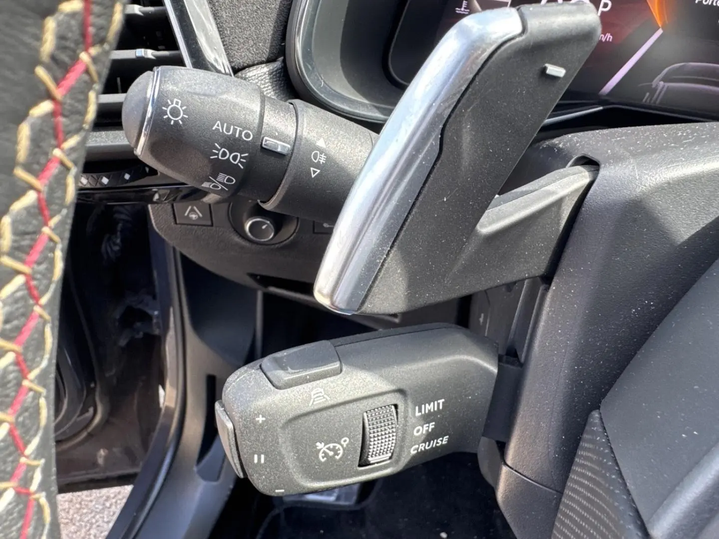 Gros plan sur commandes au volant et palettes du DS7 1.5 BlueHDi 130ch Pallas, intérieur noir avec surpiqûres rouges.
