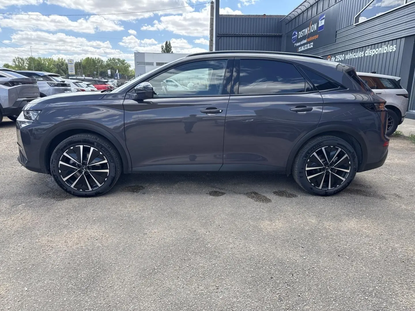 Vue latérale gauche d'un DS7 1.5 BlueHDi 130ch Pallas en gris Vol de Nuit avec jantes alliage noires et chromées.