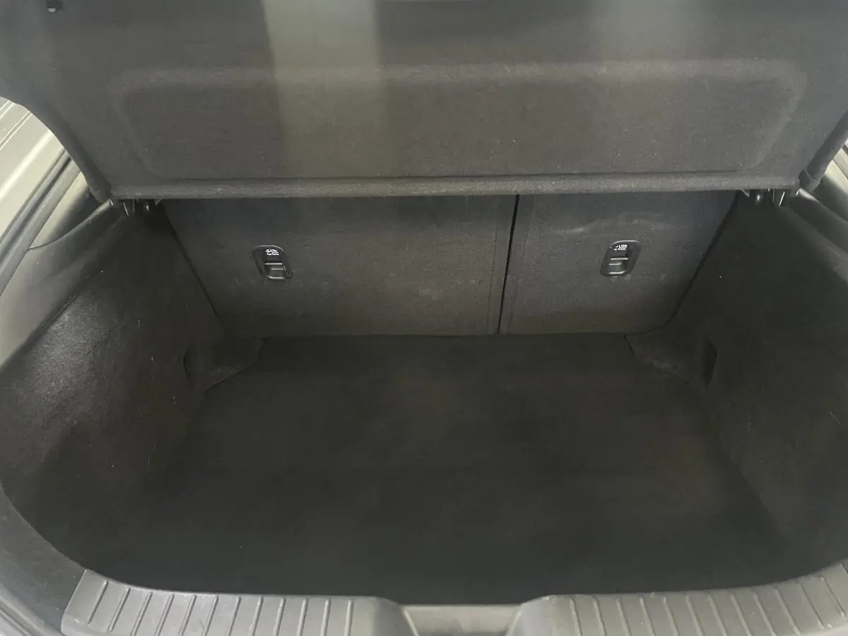 Coffre vide de la Mazda3 2.0 e-Skyactiv-G M-Hybrid gris, vue intérieure arrière avec habillage noir.