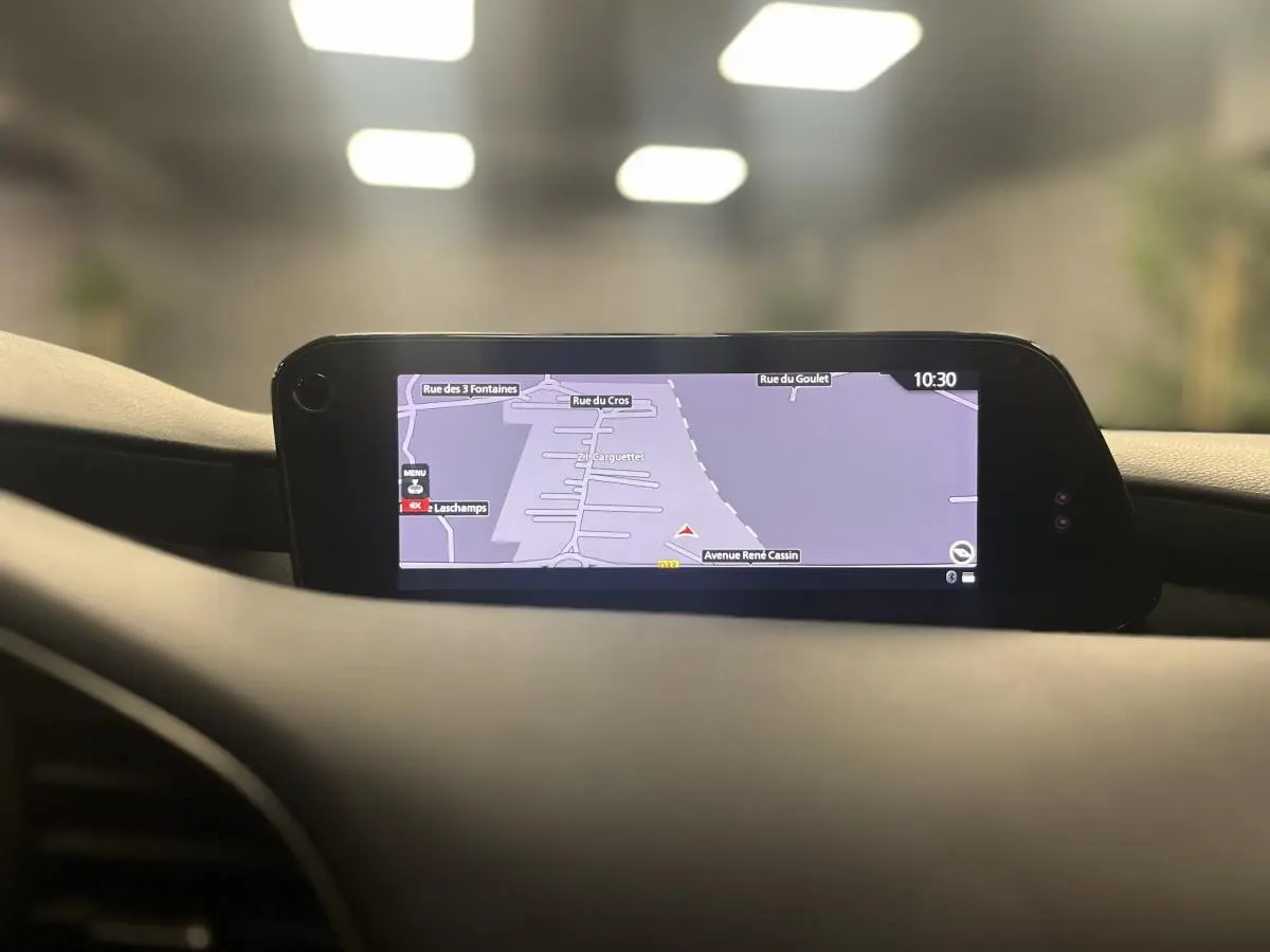 Écran central du système de navigation de la Mazda3 2023 affichant une carte routière en intérieur noir.