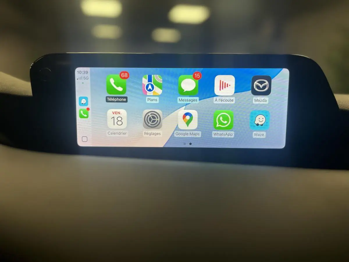 Écran central tactile affichant Apple CarPlay dans l'habitacle d'une Mazda3 gris 2023, vue de face.