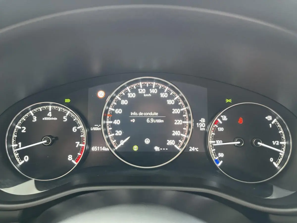 Tableau de bord de Mazda3 2023 avec compte-tours, compteur de vitesse et jauge, affichage digital central.