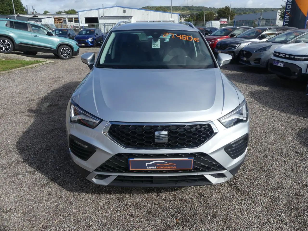 Vue frontale d'un SEAT Ateca gris clair 2023 avec calandre noire et plaques du concessionnaire visible.