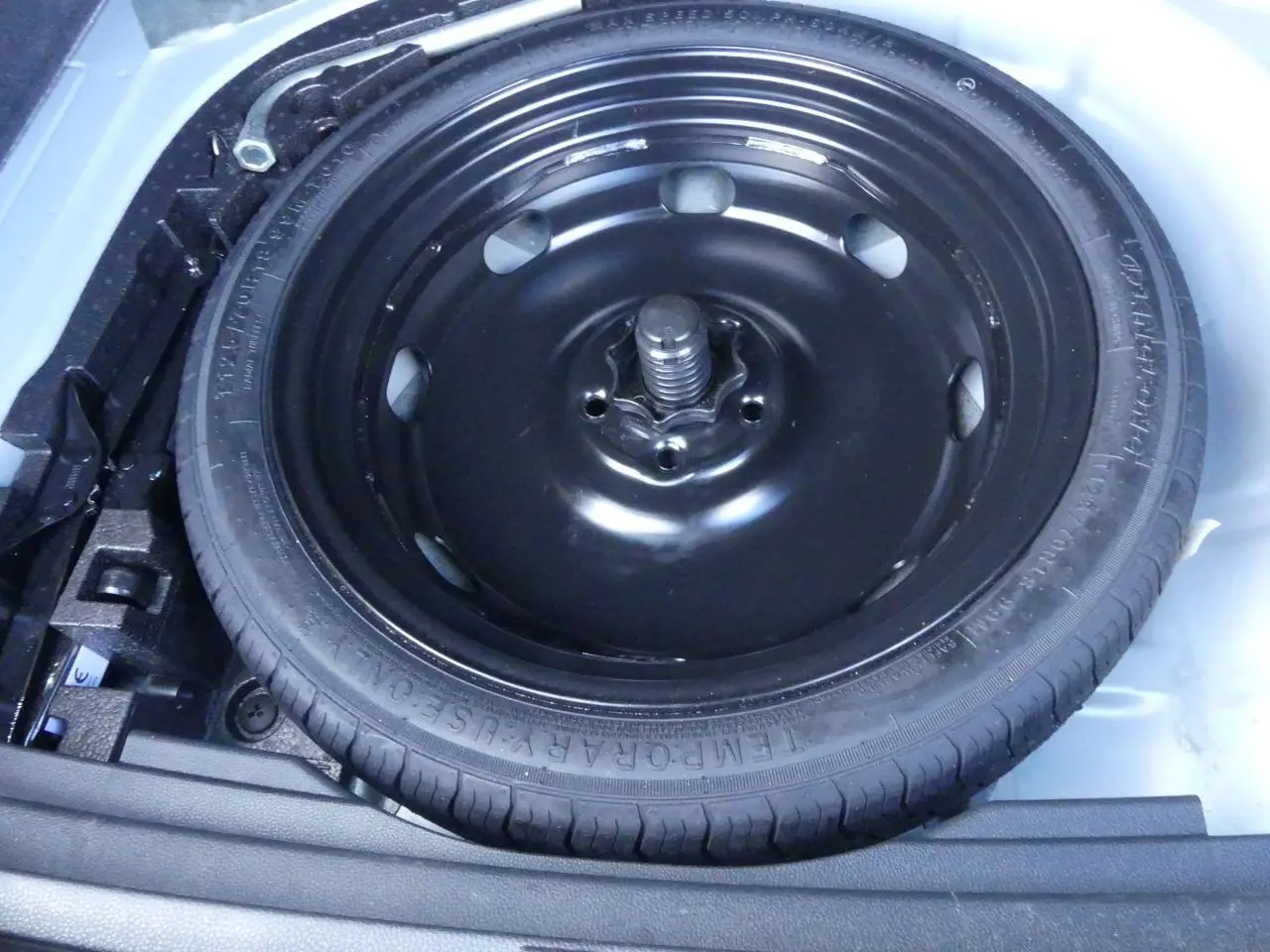 Gros plan sur la roue de secours noire dans le coffre d'un SEAT Ateca gris clair 2023.