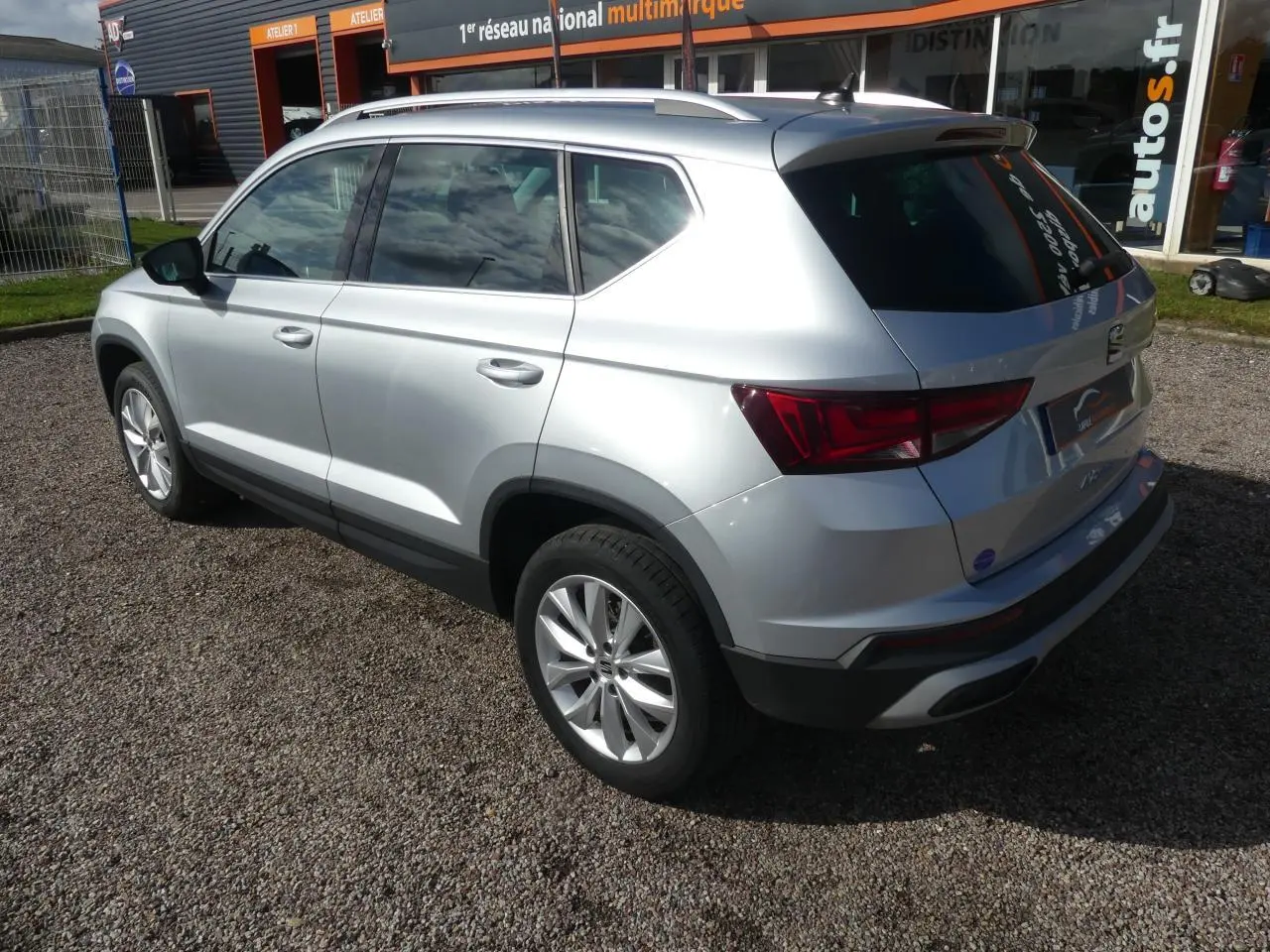 Vue 3/4 arrière droite d'un SEAT Ateca gris clair avec jantes alliage 17'' et vitres arrière surteintées.