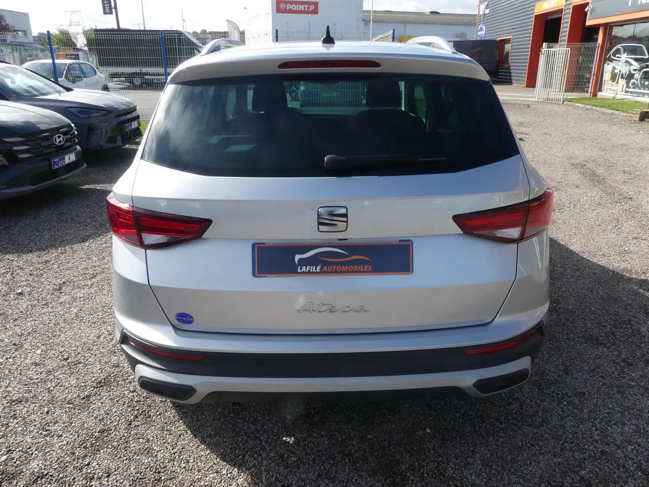 Vue arrière d'un SEAT Ateca gris clair 2023 avec feux arrière LED et hayon électrique sur un parking.
