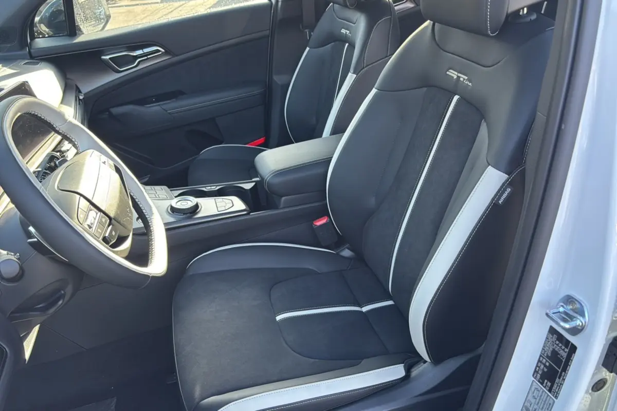 Vue intérieure côté conducteur du Kia Sportage 2026, sièges sport noirs et gris avec logo GT Line brodé.