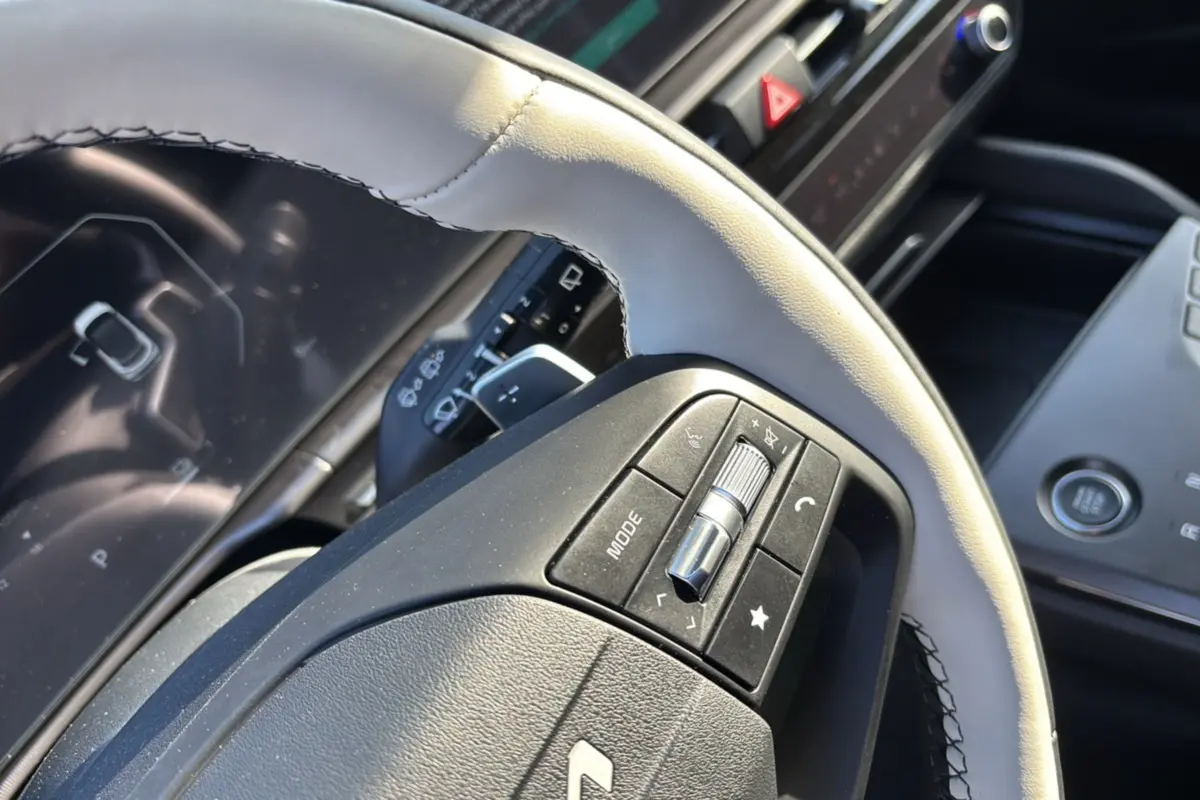 Gros plan sur le volant cuir blanc nacré avec commandes multifonctions du Kia Sportage 2026 hybride, tableau de bord en arrière-plan.